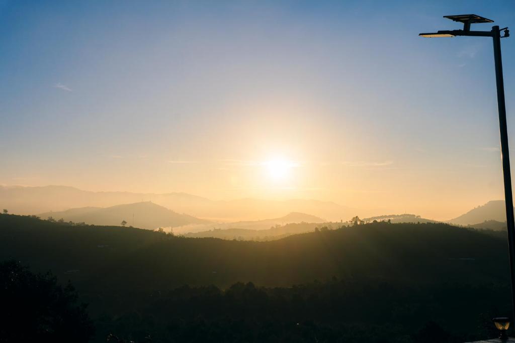 Una puesta de sol sobre un valle con una farola en THỎ NON GARDEN CLOUDY OCEAN VIEW, en Blao Srê