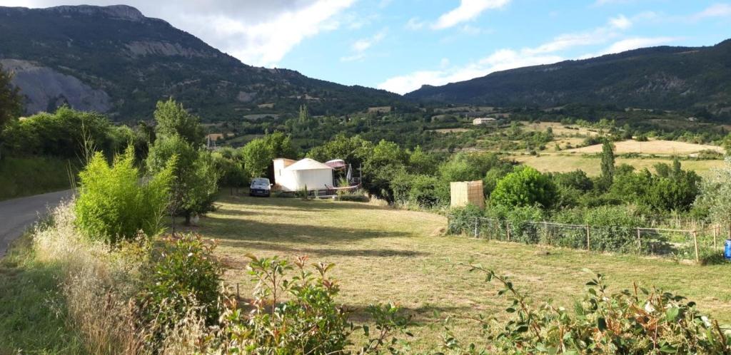 a house in a field with mountains in the background at La Yourte Des Abeilles in Les Preyrauds