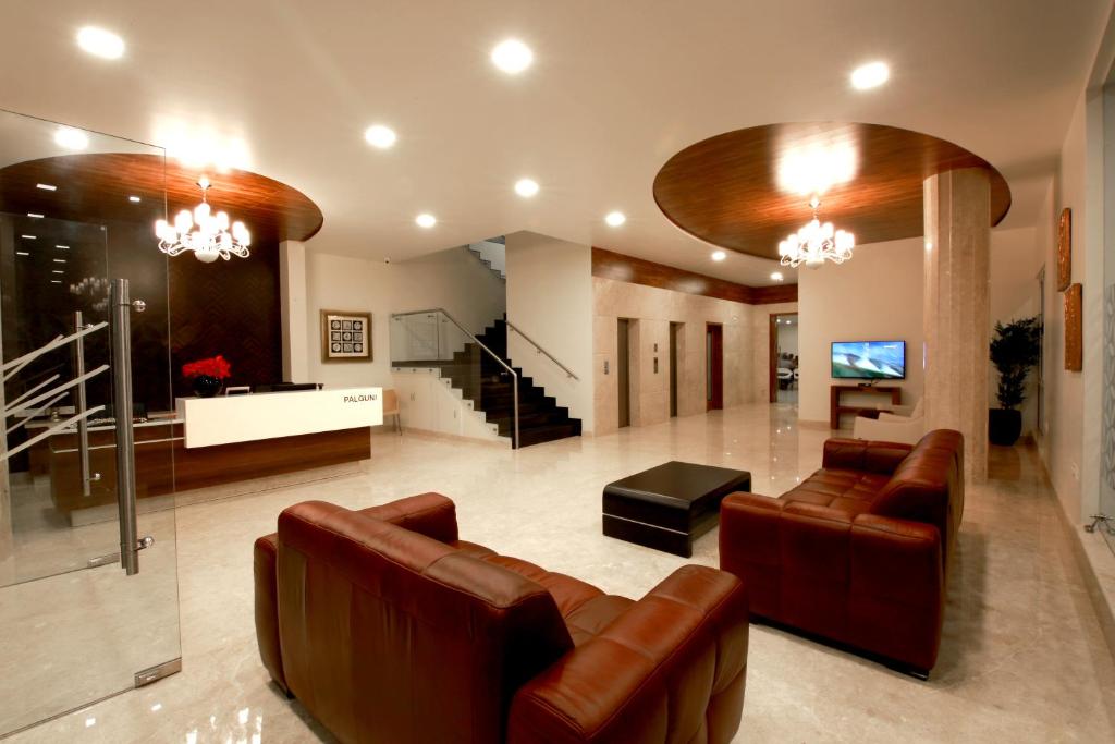 uma sala de estar com sofás de couro e uma televisão em Palguni Residency em Hassan