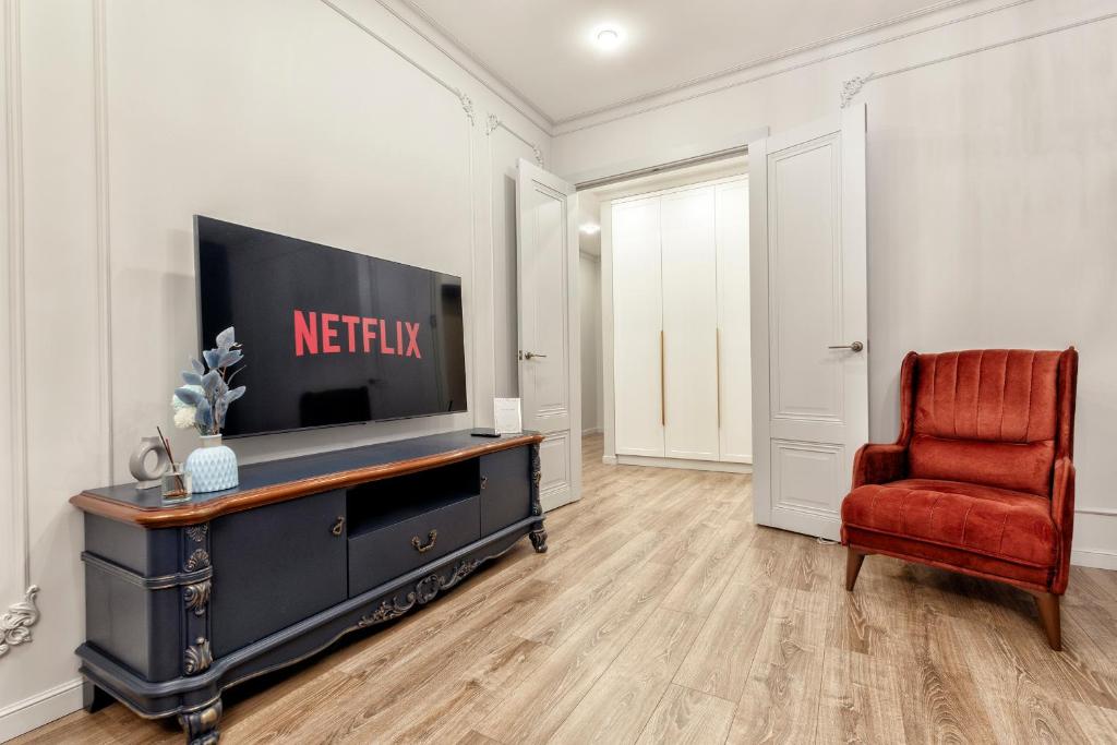 Большая двухкомнатная Люкс возле вокзал НУРЛЫЖОЛ في أستانا: غرفة معيشة فيها تلفزيون وكرسي احمر