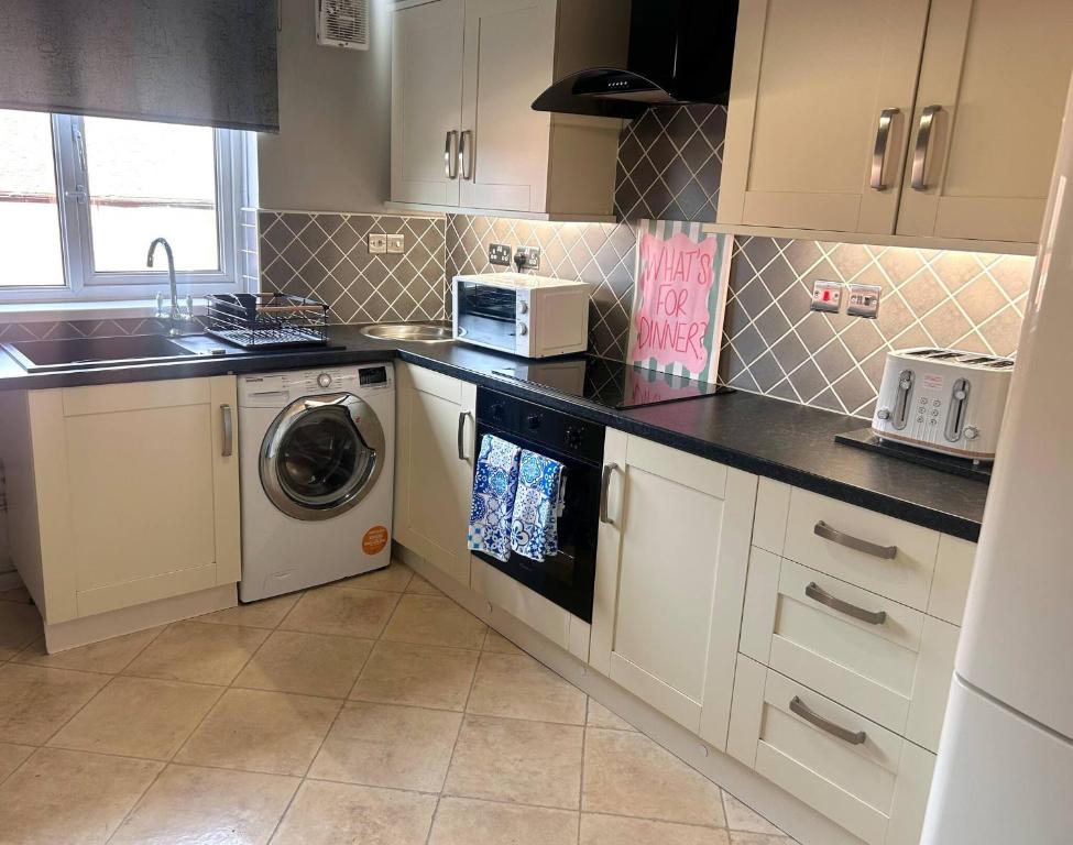 een keuken met witte kasten en een wasmachine bij Churchill Apartment- 4 Beds- Free Parking- Near NEC BHX & HS2 in Coleshill