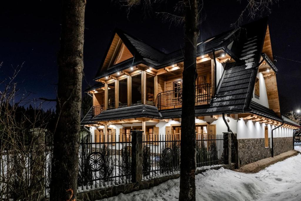 a house in the snow at night at Czorna Chata u Chocyków & SPA in Czarna Góra