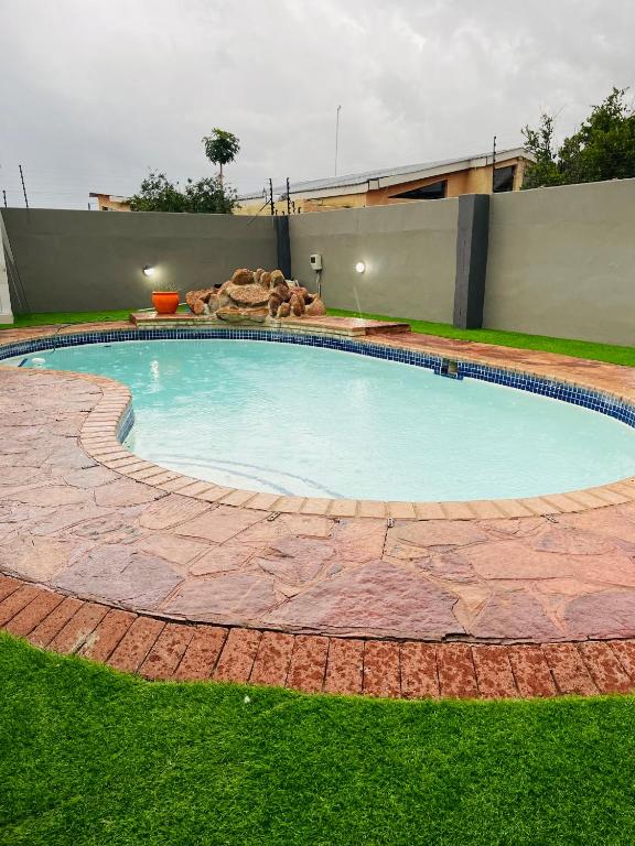 Que Self Catering Apartments - Block7 في غابورون: مسبح كبير وحوله مسار طوب