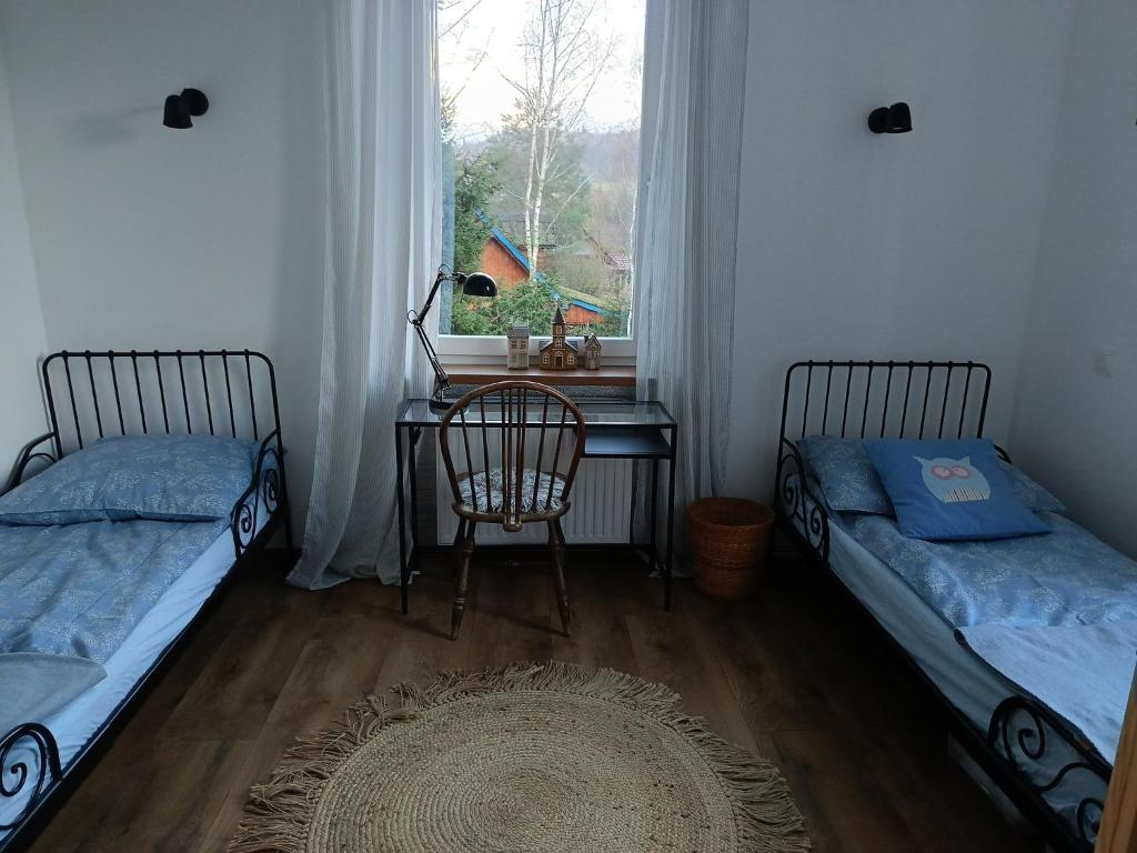 a room with two beds and a desk and a window at Apartament w Starej Szkole in Zagórze Śląskie