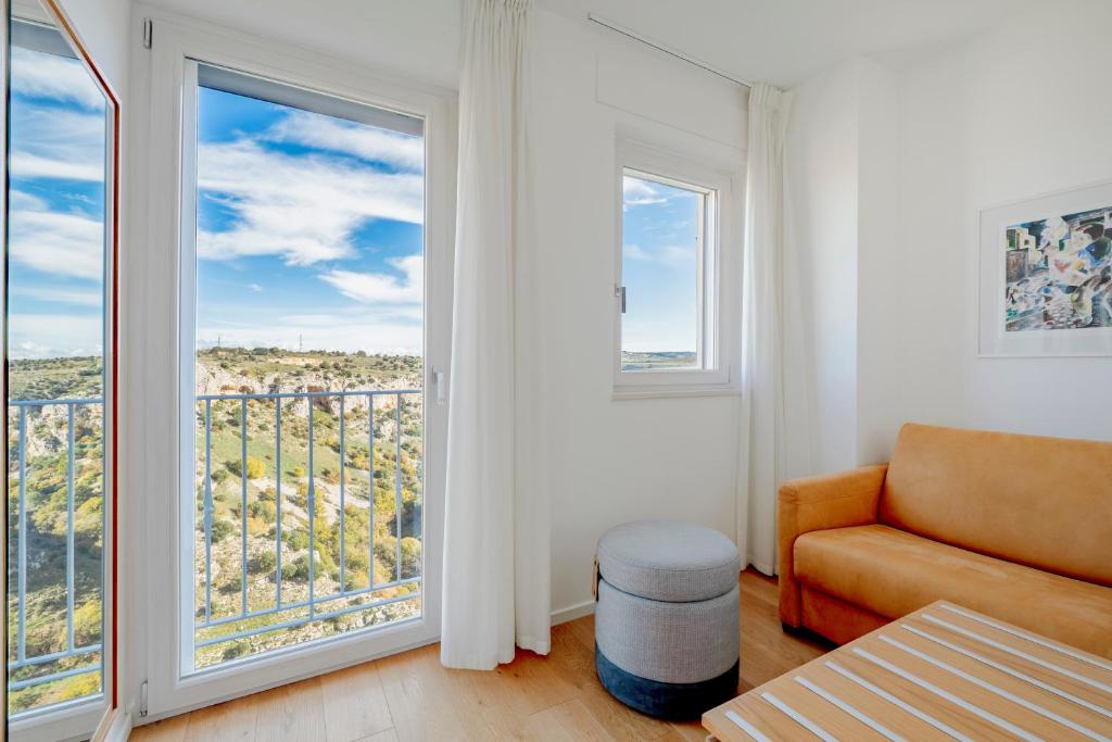 a living room with a couch and two large windows at Casa Festa Rooms in Matera