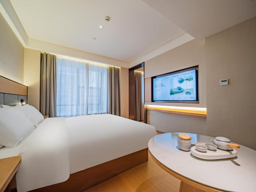 ein Hotelzimmer mit einem großen Bett und einem Tisch in der Unterkunft JI Hotel Chengdu Sichuan Normal University in Chengdu