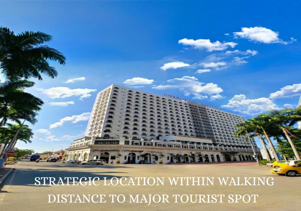 a large white building on a street with palm trees at Imperial Heritage Hotel Melaka I City Centre I Free Wifi I Free Parking l Free Club Lounge Access in Melaka