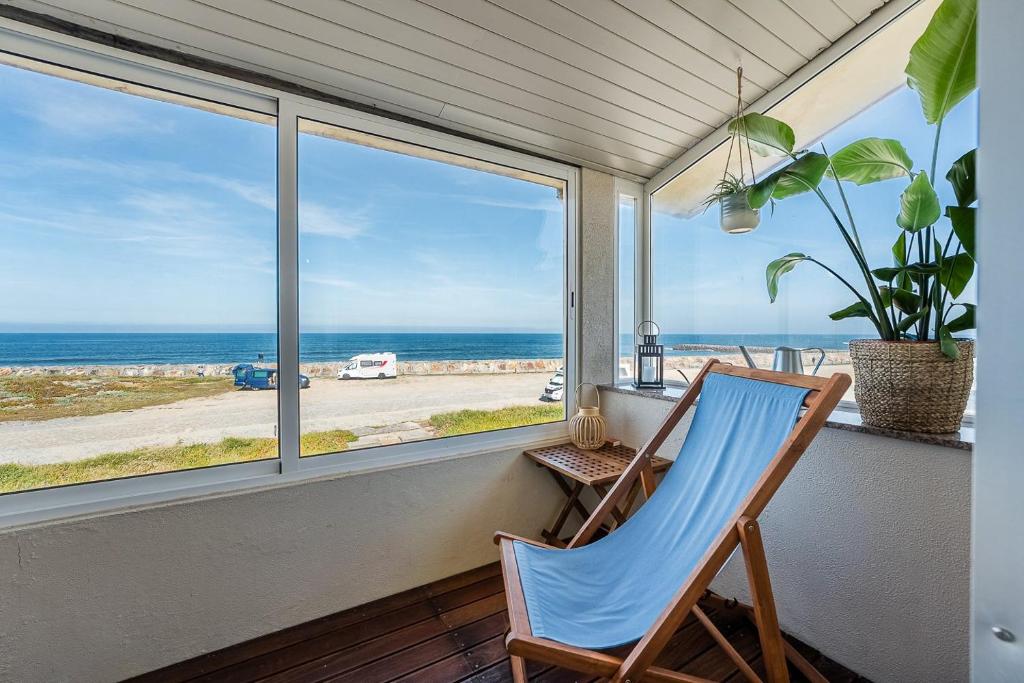 a chair on a porch with a view of the ocean at Charming Beachside Escape in Esmoriz