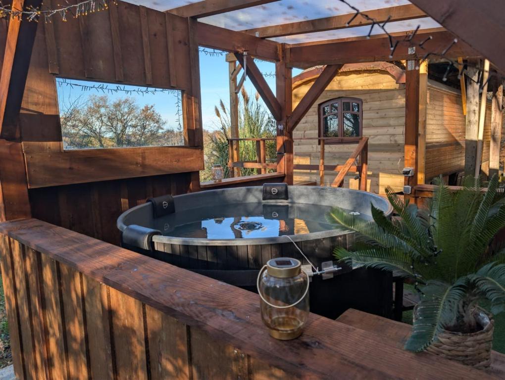 a hot tub on the deck of a house at Roulotte avec bain nordique privatif chauffé, Séjour calme et bien-être in Fichous-Riumayou