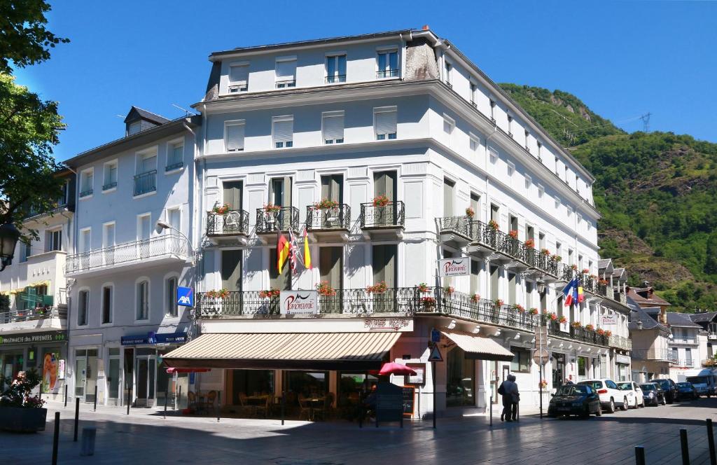 ein großes weißes Gebäude mit Balkon auf einer Straße in der Unterkunft Hôtel Panoramic in Luchon