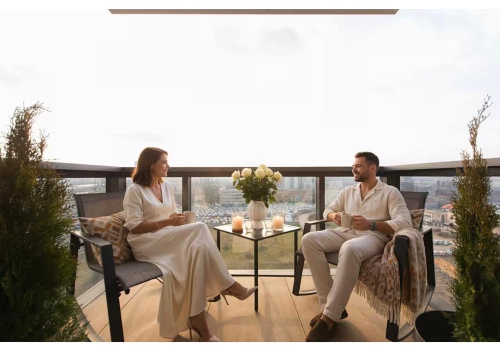 un homme et une femme assis sur un balcon dans l'établissement Cortina North - Modern Studio Apartment with Balcony, à Voluntari