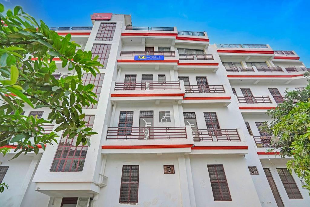 FabHotel Hare Rama في Prayagraj: مبنى أبيض طويل مع شرفات وأشجار