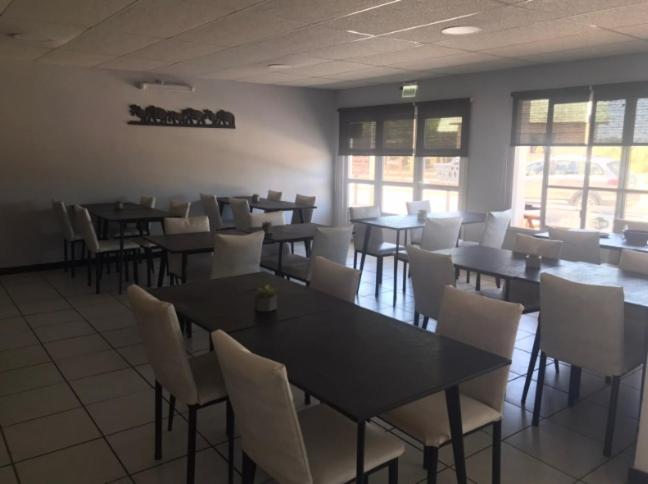 Hotel Romalu في سانتا تيريسيتا: غرفة طعام مليئة بالطاولات والكراسي البيضاء