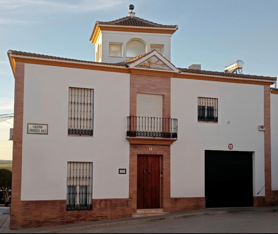 a white building with a clock tower on top at DescubreHome La Casa del Medico in Aznalcázar
