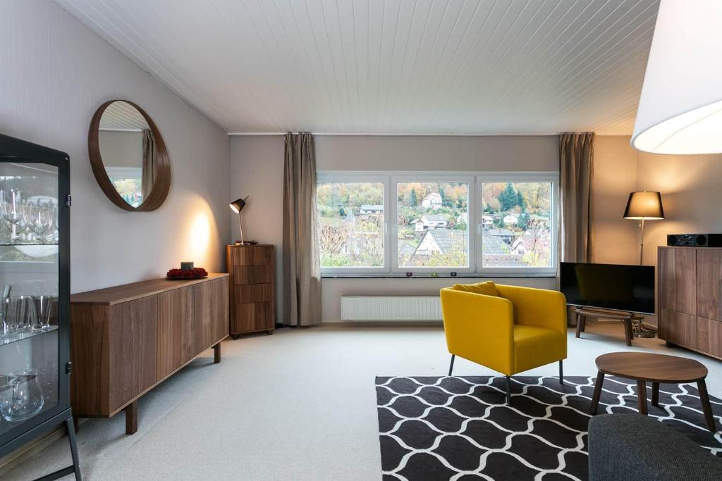 a living room with a yellow chair and a mirror at Haus am Sagenweg in Nothweiler