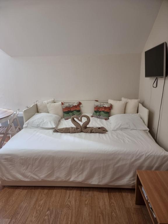 a large white bed with a pair of brown snakes on it at La Poudreuse Résidence les Balcons d'Aix in La Féclaz