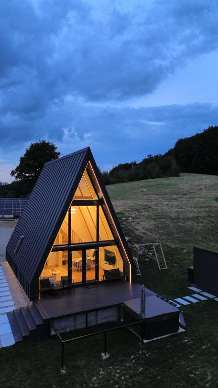 ŞeraniAir Cabin, Cabana tip A-frame in Șerani, Bihor的田野上黑屋顶的小房子