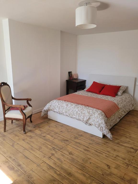 a bedroom with a bed with red pillows and a chair at la maison du grand mas in Mouret
