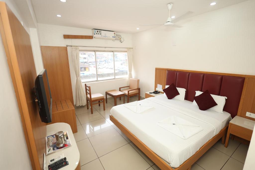 a bedroom with a bed and a desk and a television at Hotel Janardana in Udupi