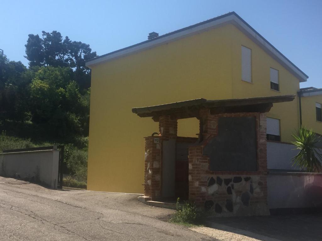 una casa amarilla con garaje de piedra y ladrillo en Le Villette, en Pescara