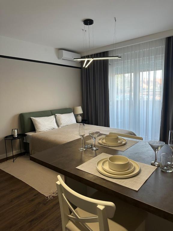 een slaapkamer met een bed en een tafel met borden en glazen bij Premium Line Apartman 3 in Sombor