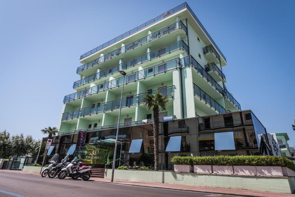 un alto edificio verde con moto parcheggiate di fronte di Hotel Taormina a San Benedetto del Tronto