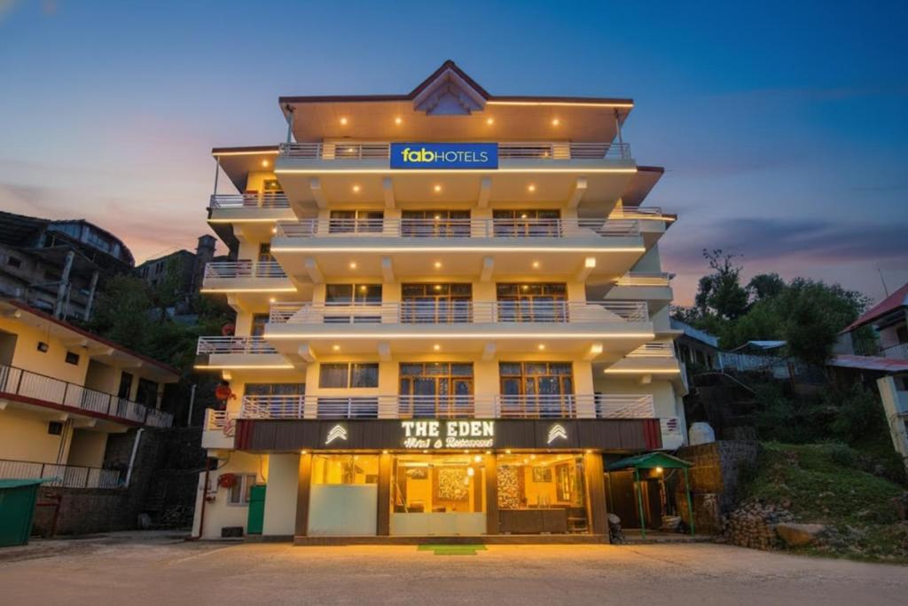 a tall white building with a sign on it at FabHotel The Eden in Dharamshala