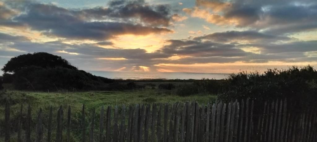 a fence in a field with a sunset in the background at Studio face à l océan in Les Sables-dʼOlonne