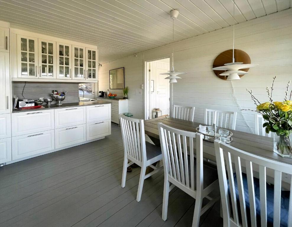 Una cocina con gabinetes blancos y una mesa y sillas. en Cozy Cabin With Sea View And Two Terraces, en Tjøme