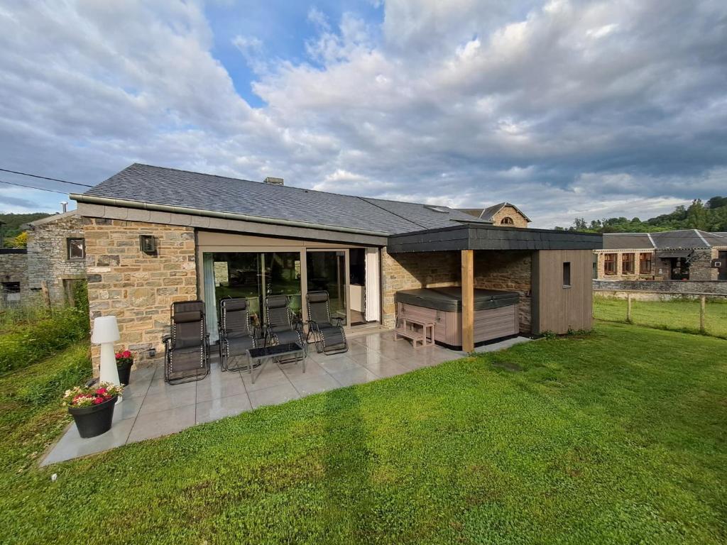 a house with a patio with chairs and a grill at Au pied de La Redoute in Sougné-Remouchamps