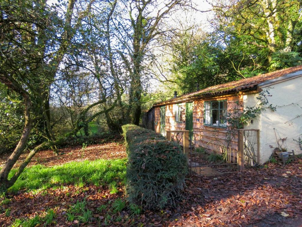 an old house with a bush next to it at Bluebell Cottage At Lurley Manor in Washfield