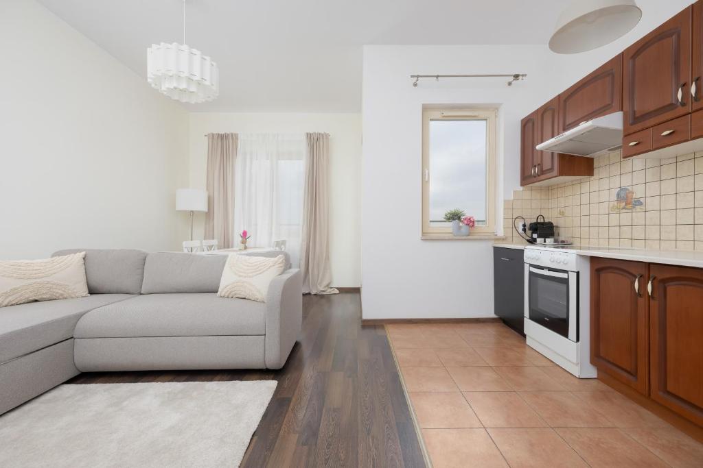 a living room with a couch and a kitchen at Pool & Cozy Apartment Warszawa Bukowińska by Solarento in Warsaw