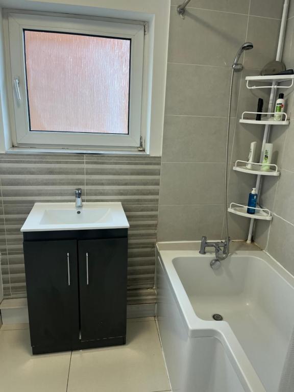 a bathroom with a sink and a tub and a window at Spacious 4 bedroom apartment with parking in Leavesden Green
