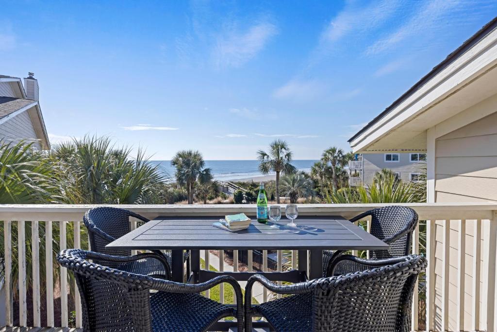 a table and chairs on a balcony with the ocean at SG3C: 3C Seagrove Villa in Isle of Palms