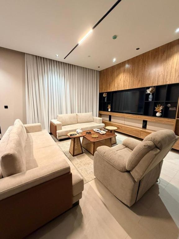 a living room with two couches and a flat screen tv at Luxury Apartment شقه الفخامه في المونسيه in Riyadh