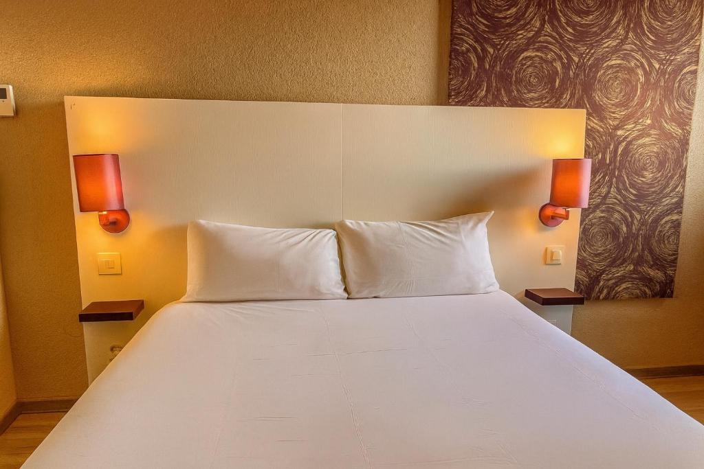 Una gran cama blanca con dos luces en la pared. en The Originals City, Hôtel Mulhouse, Ile Napoleon, en Rixheim