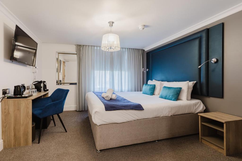 a hotel room with a large bed and a desk at The Porchester Hotel in London