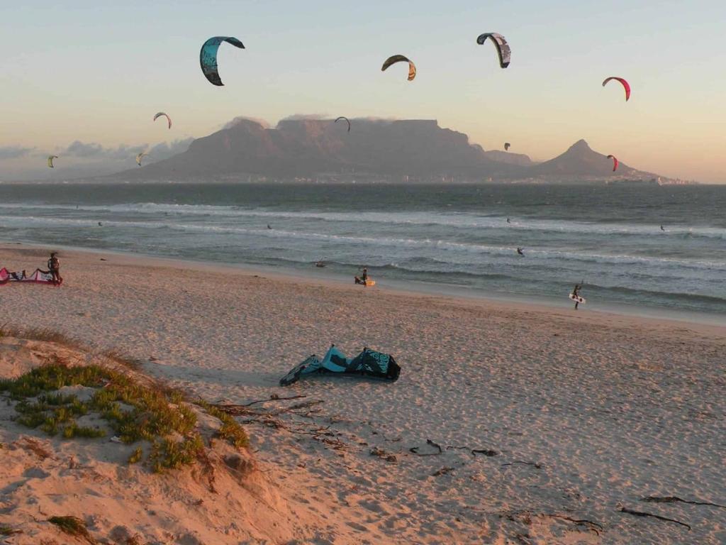 a group of people flying kites on a beach at Beach Vibes Villa in Cape Town