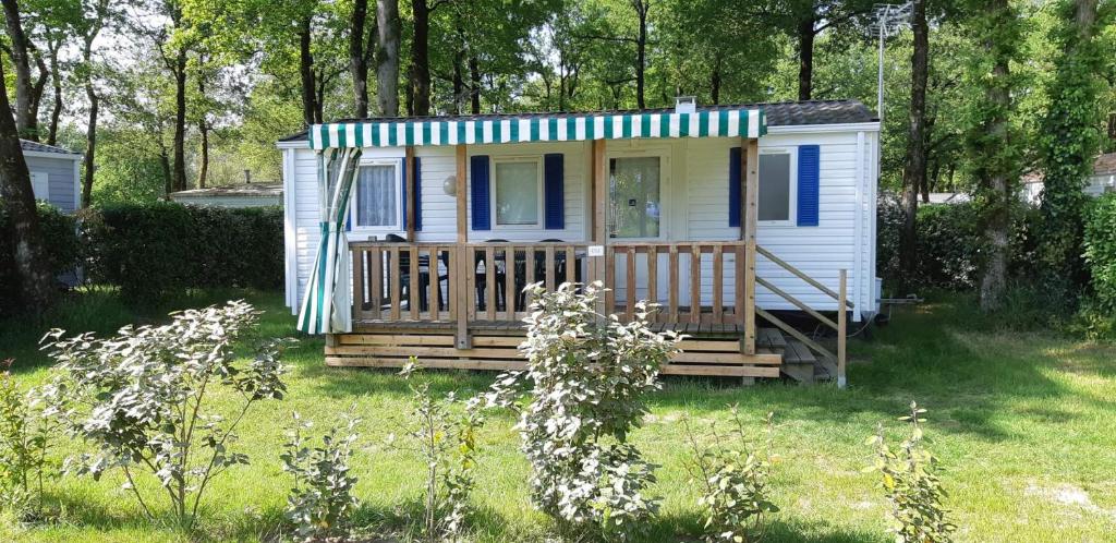 Una pequeña casa con porche y rayas azules y blancas. en mobile home 6 personnes-3 chambres, en La Boissière-de-Montaigu