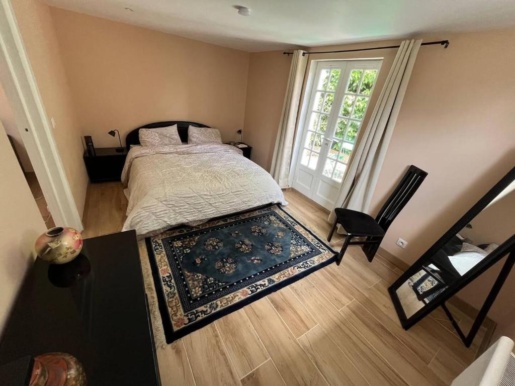 een slaapkamer met een bed met een tapijt en een raam bij Maison cosy avec jardin & parking, proche Disney in Chelles