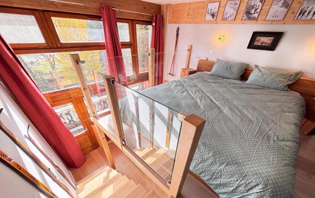 a bedroom with a bed and a staircase with a window at L'appart du Yeti, cocon rénové avec goût, multipass été, ménage et linges compris in Les Gets