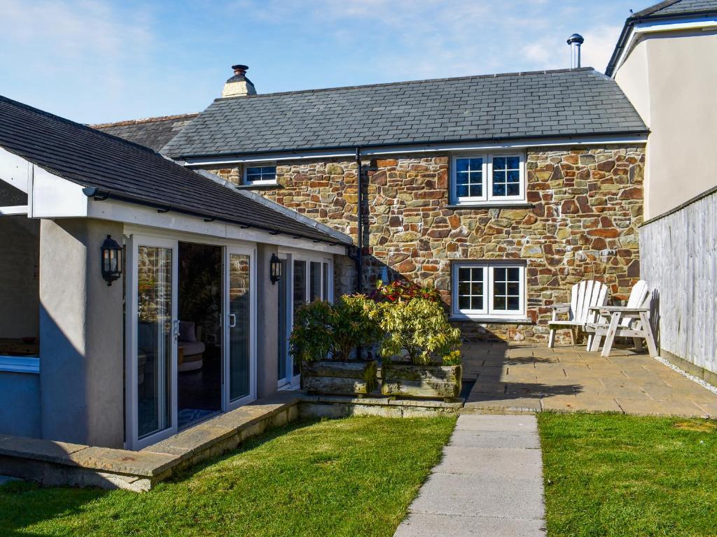 Honeysuckle Cottage في High Bickington: منزل حجري امامه فناء