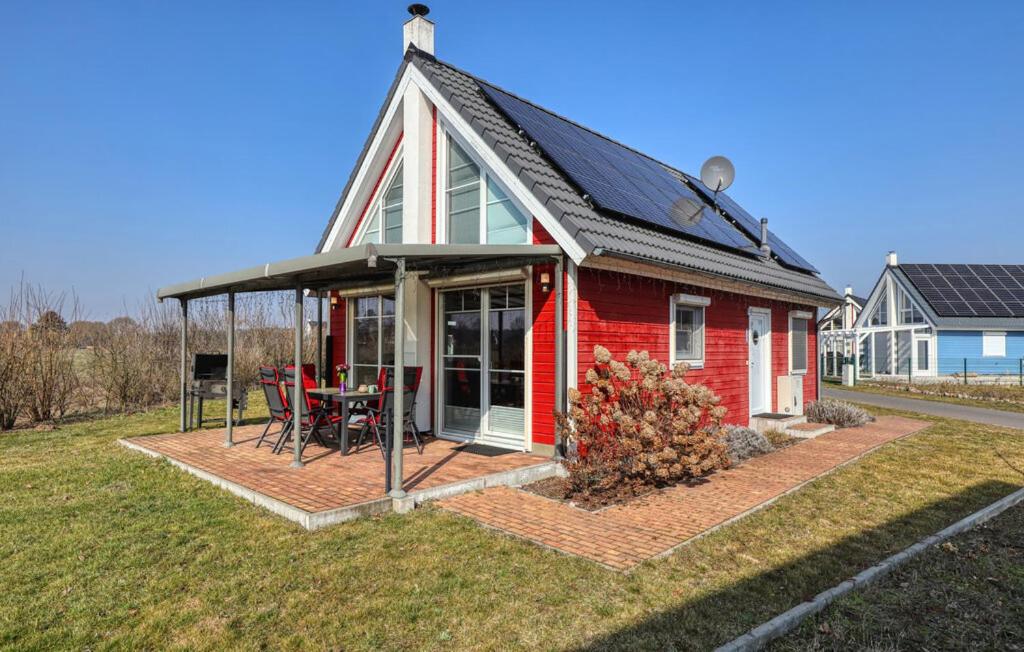 a red house with a pitched roof and a table at Haus Feldblick in Wandlitz