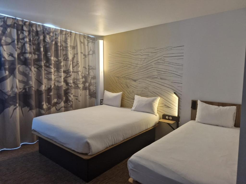 マシーにあるB&B HOTEL Massy Gare TGVのベッドルーム1室(ベッド2台、カーテン付)