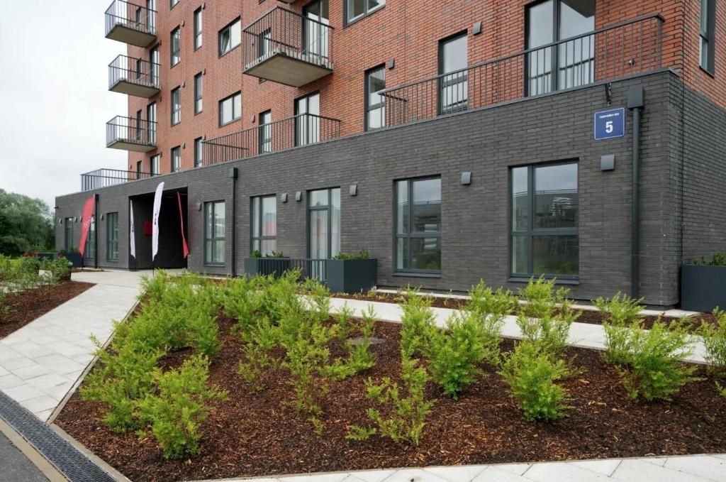 Riga Riverside Escape Lucavsala, Close to City Center في ريغا: عمارة سكنية أمامها نباتات
