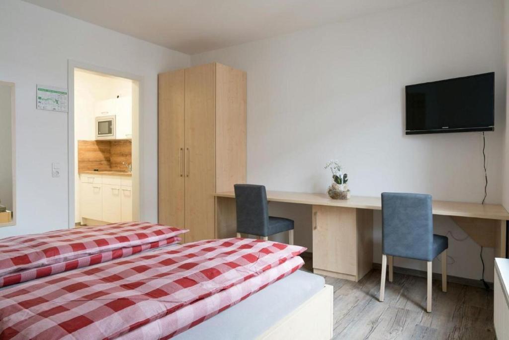 a bedroom with a bed and a desk with two chairs at Anitas Altstadtpension in Kelheim