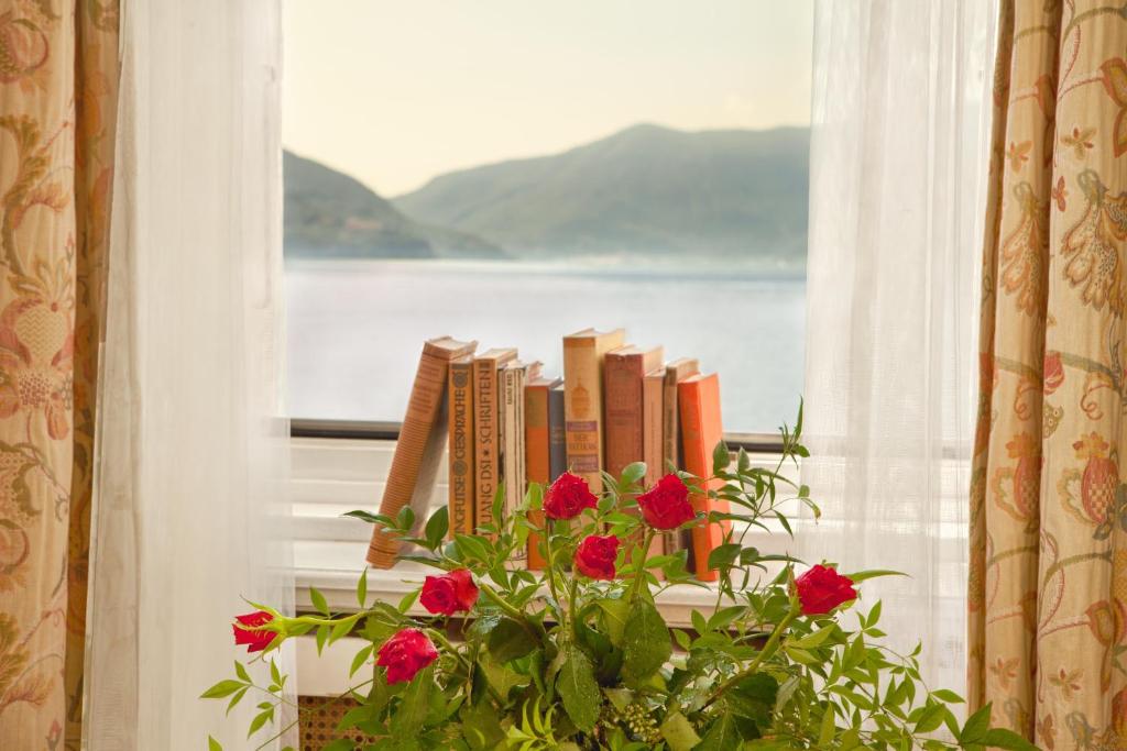 a window with a pile of books and a flower at Hotel Tamaro in Ascona