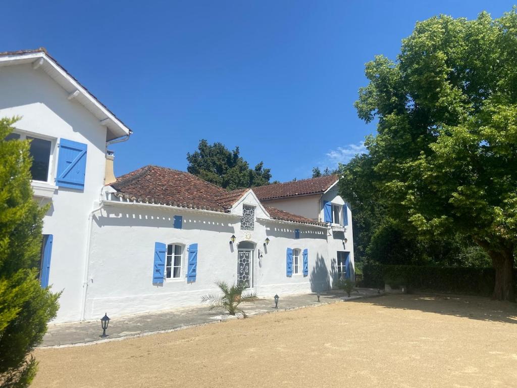 una casa bianca con finestre blu e un cortile di Ancienne ferme Gersoise a Riscle