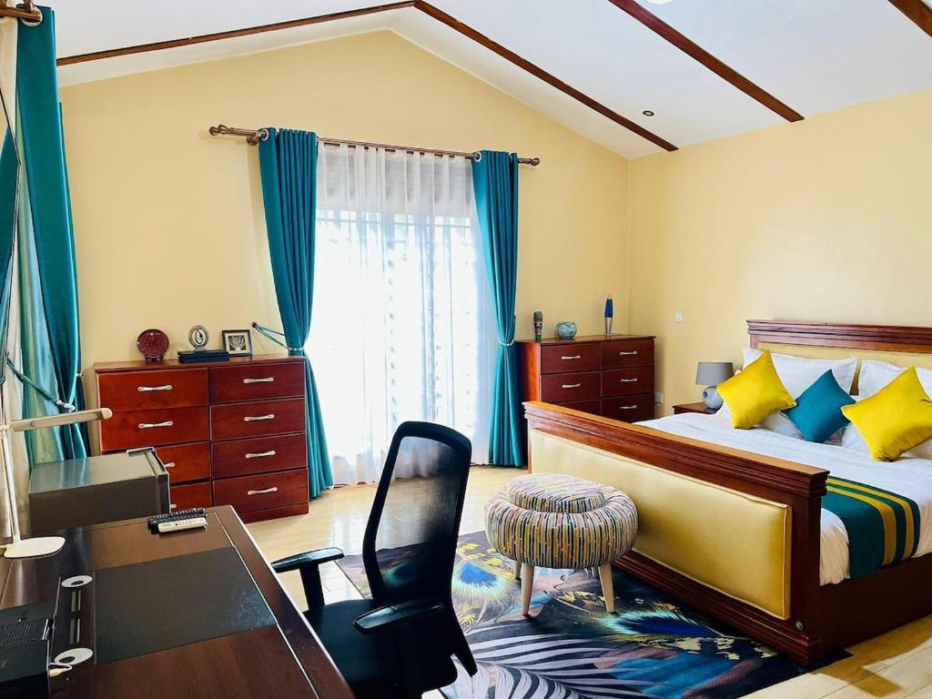 a bedroom with a bed and a desk and a chair at Maison Princeton in Kampala