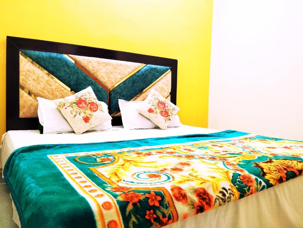 a bed with a colorful blanket and pillows on it at "Om Sadan" Ayodhya Dhaam in Ayodhya
